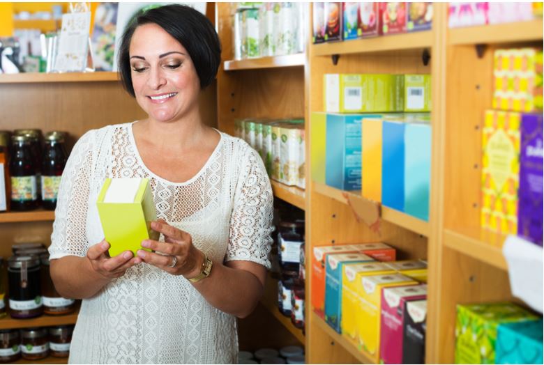 Photo of woman holding a box of supplements in a shop aisle